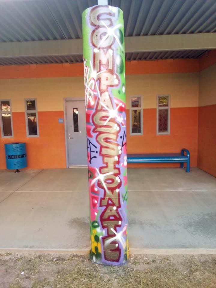 A pillar painted in a street art style featuring the word: Compassionate