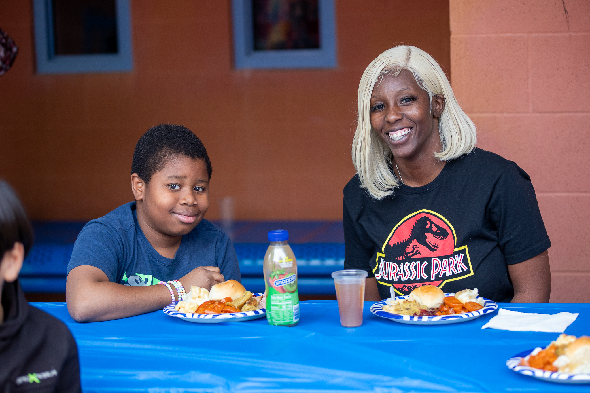 A boy and his mom smile at a table with their plates full of Thanksgiving food