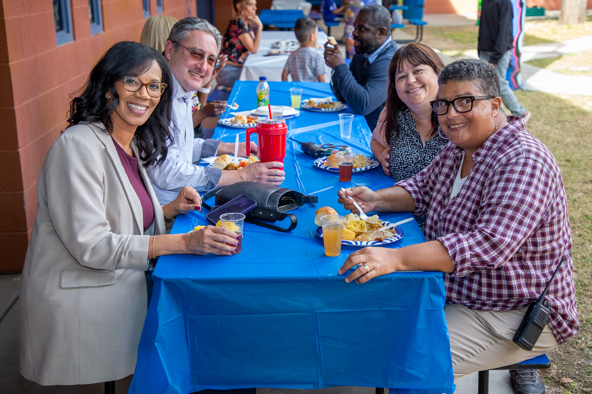 A table of staff members smile with their meals