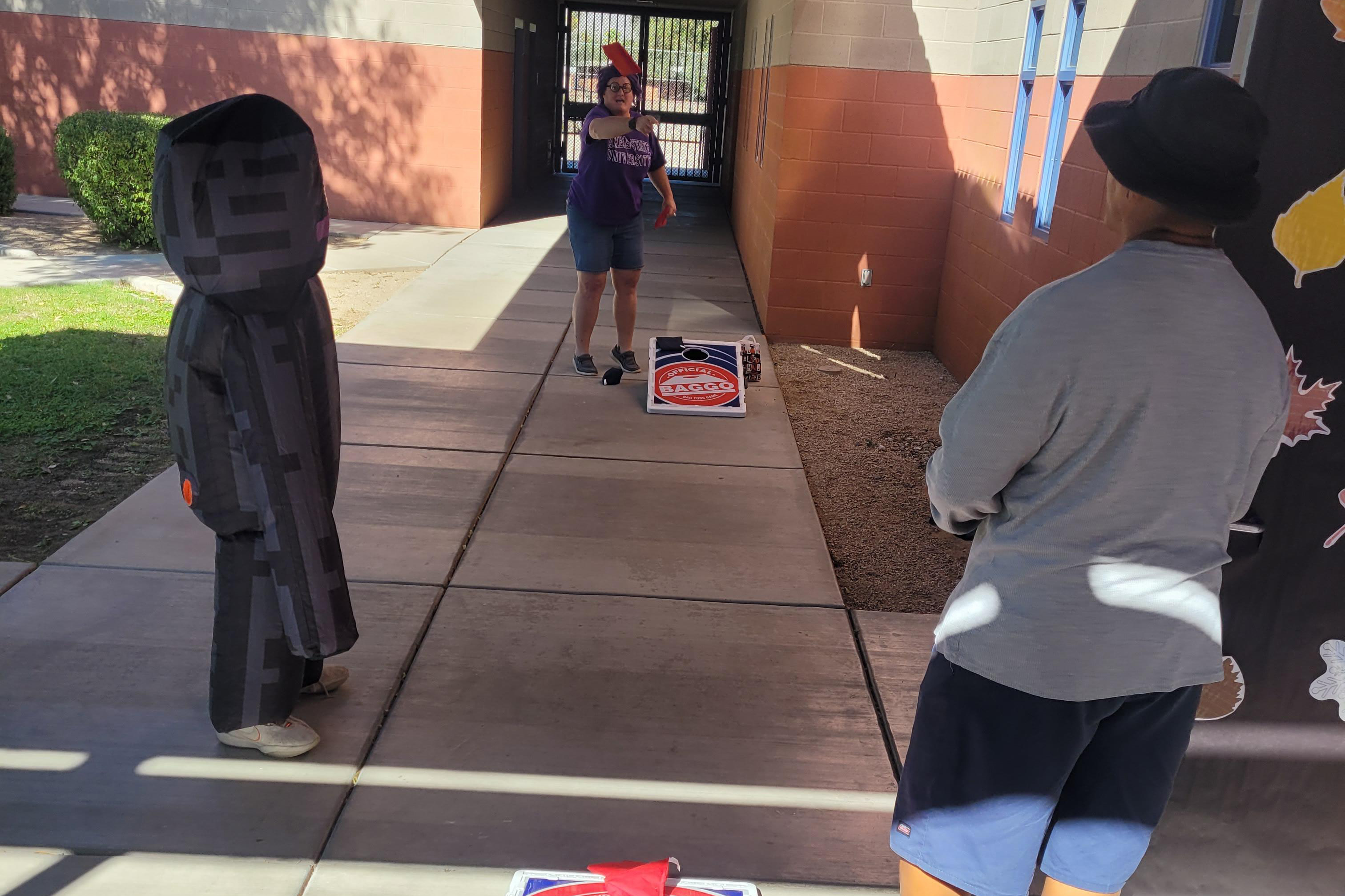 A woman tosses a bean bag into a cornhole board