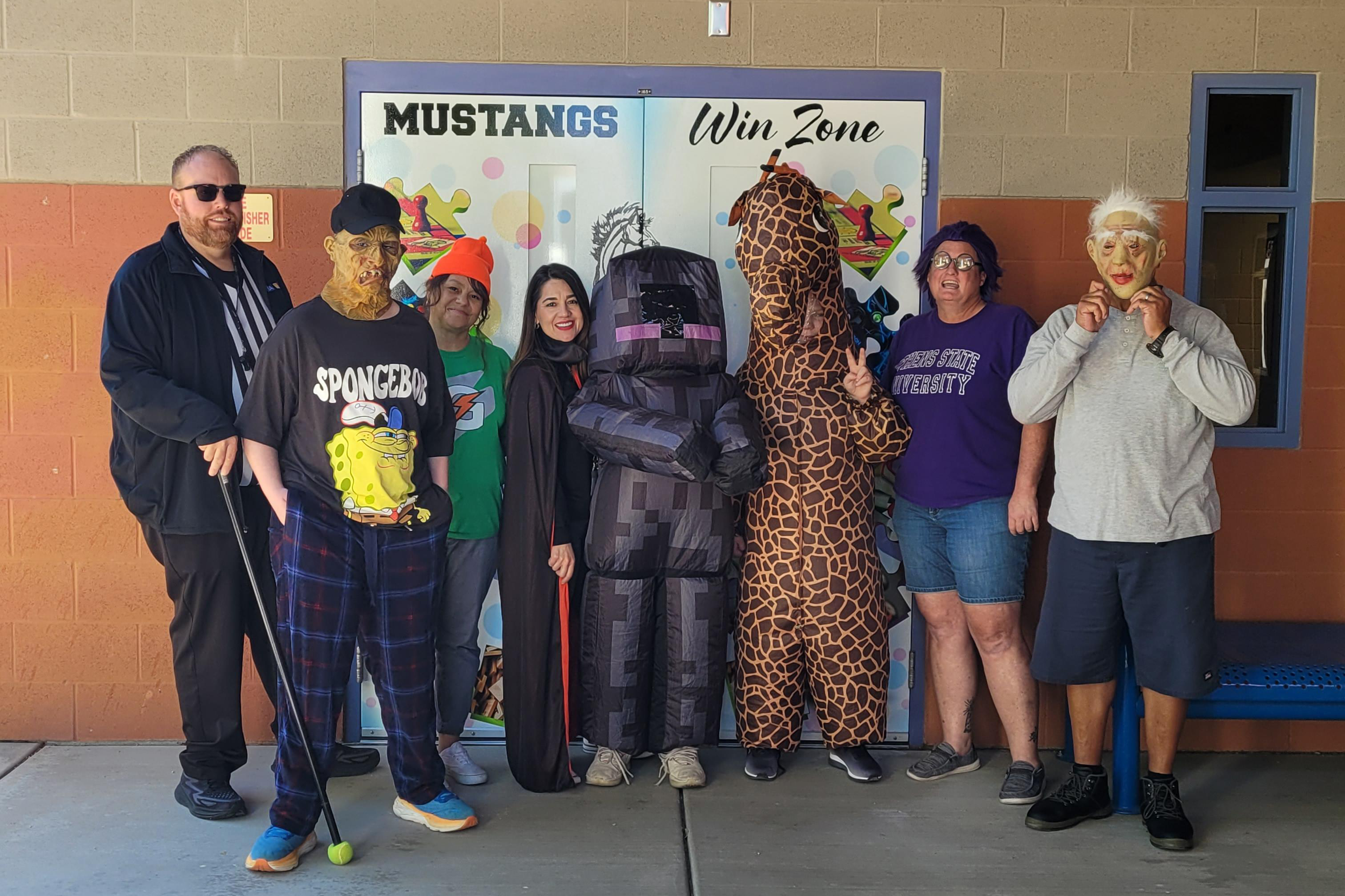 A group of eight adults pose for a photo in their Halloween costumes