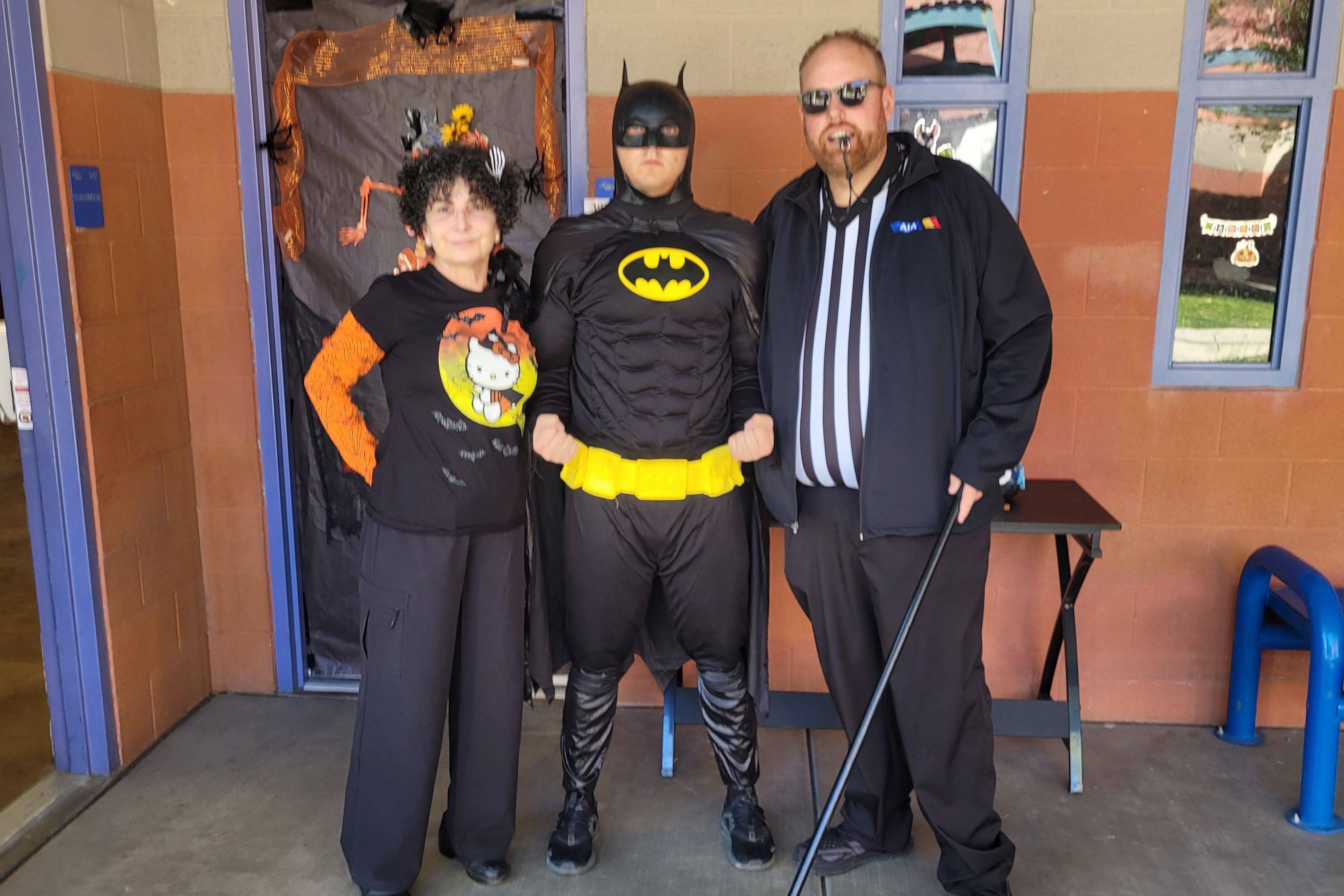 Three adults pose for a photo in their Halloween costumes