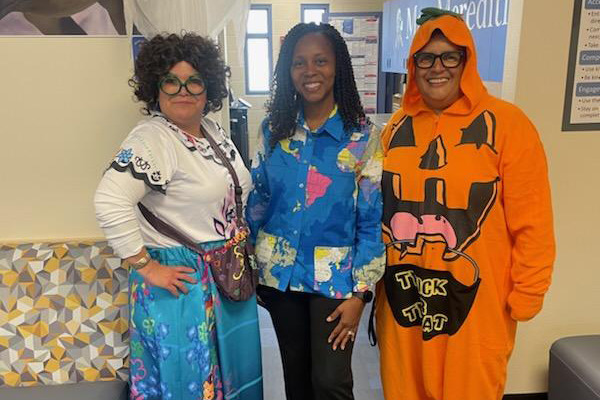 Three women smile in Halloween costumes