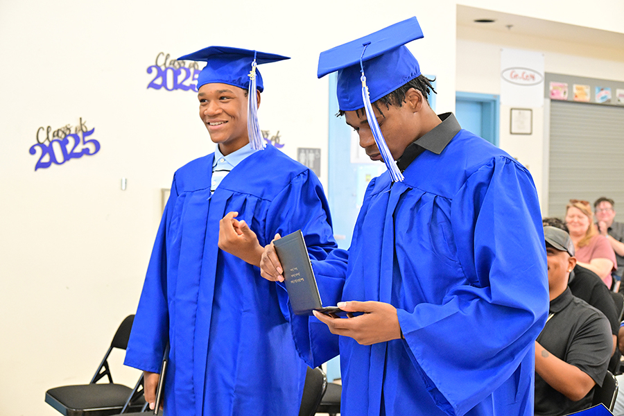 The two graduates walk together in their blue caps and gowns