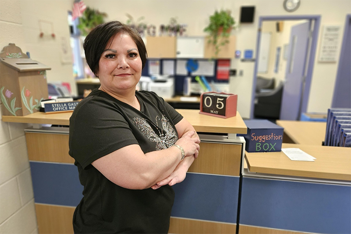 A woman with short dark hair crosses her arms in front of the front desk