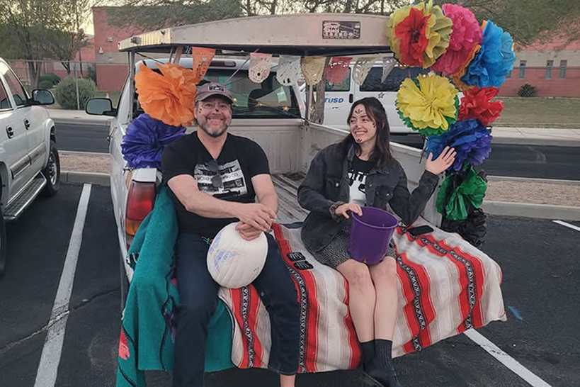 A man and woman smile in the back of their decorated pickup truck