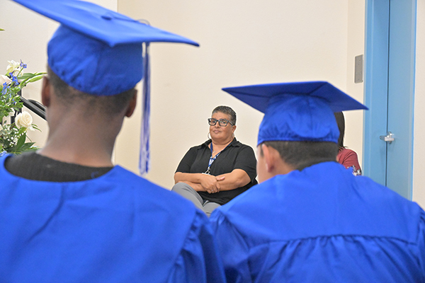 The two graduates sit watching the ceremony in their blue caps and gowns