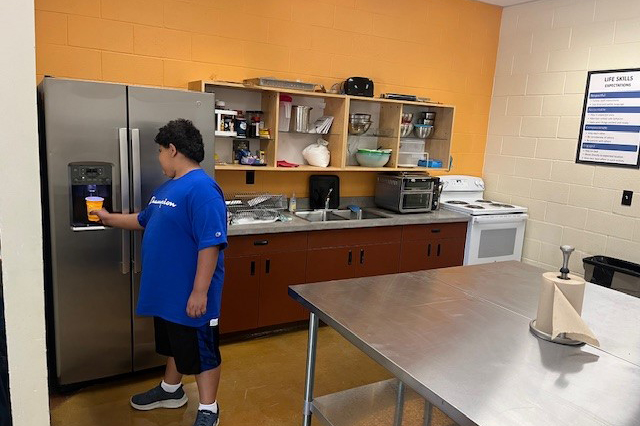 A boy in a blue shirt gets water from a stainless steel fridge
