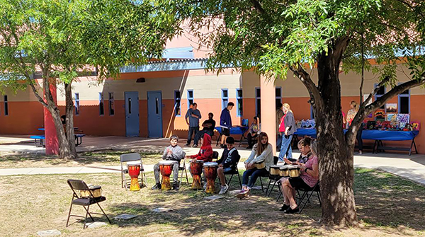 Students playing instruments under a large tree
