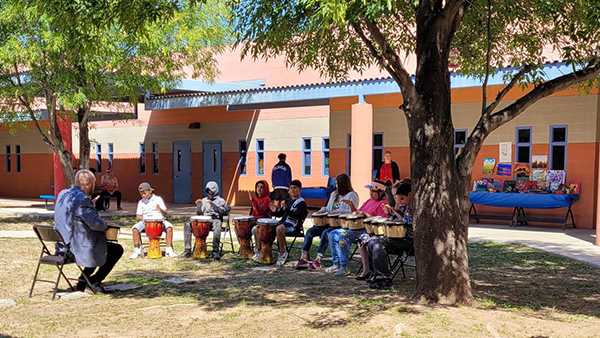 Students playing instruments under a large tree