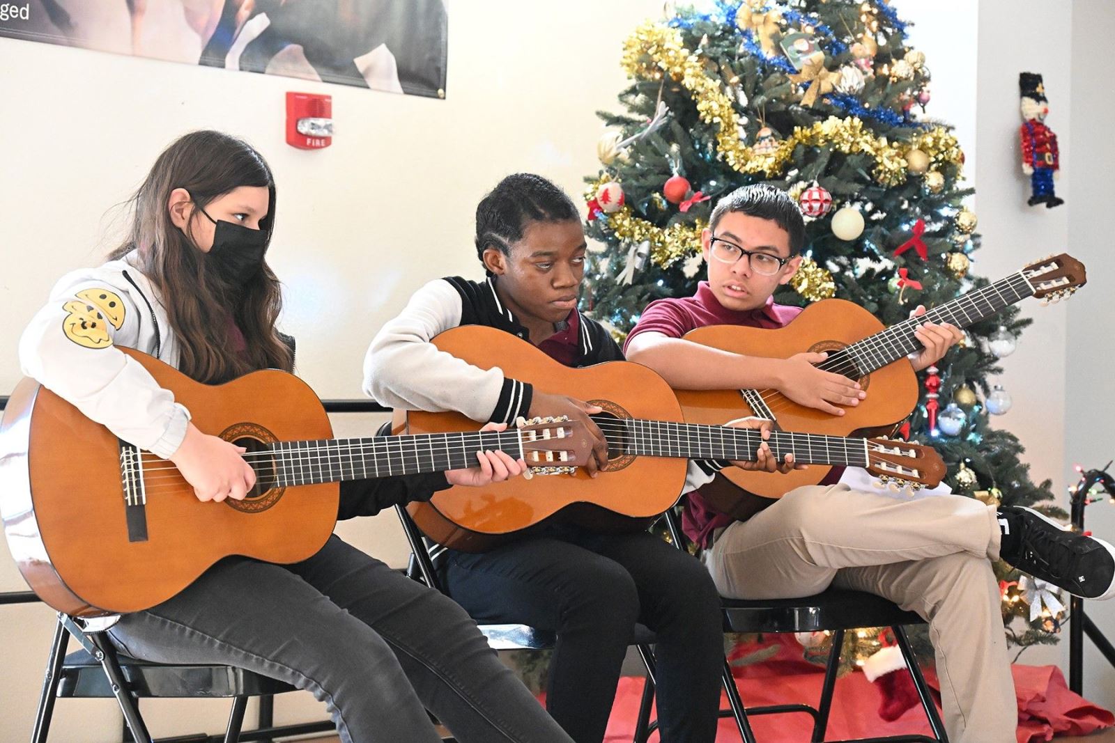 Three students play Christmas songs on the guitar.